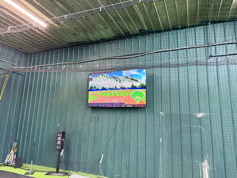 Indoor batting cage with HitTrax screen at Chenango SportsZone
